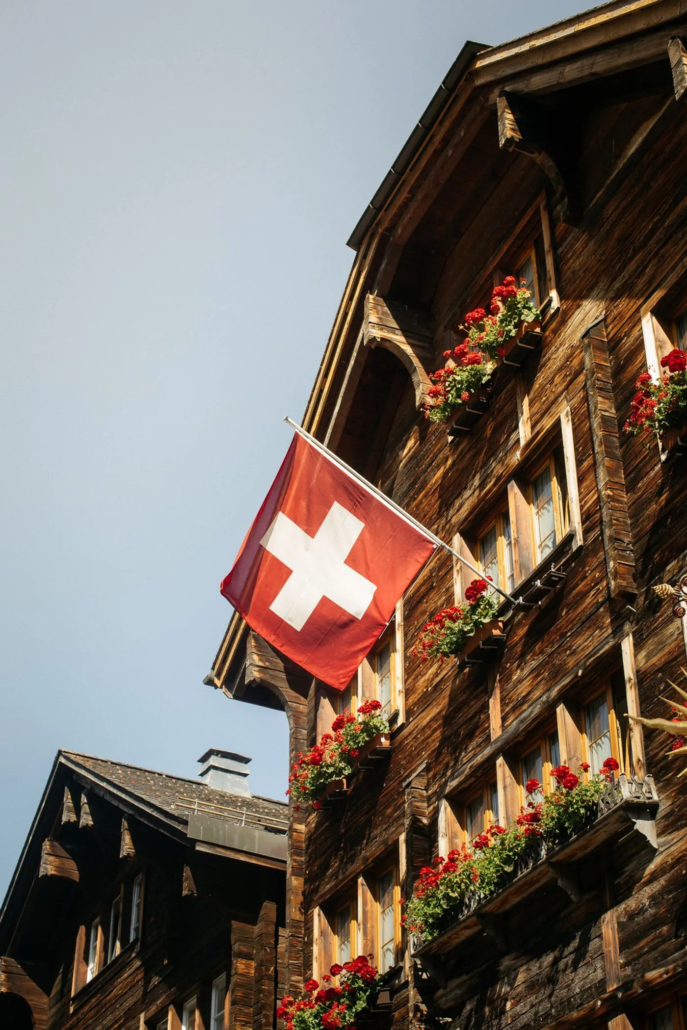 Swiss flag on a traditional timber chalet with red geraniums