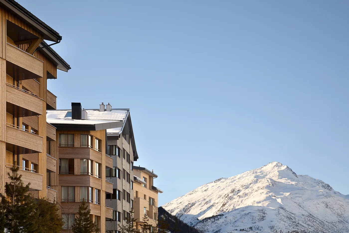 Timber apartment buildings in Andermatt Reuss with peaks behind